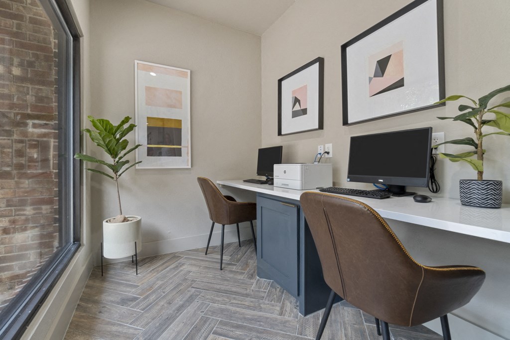 a home office with two desks and a computer and a window