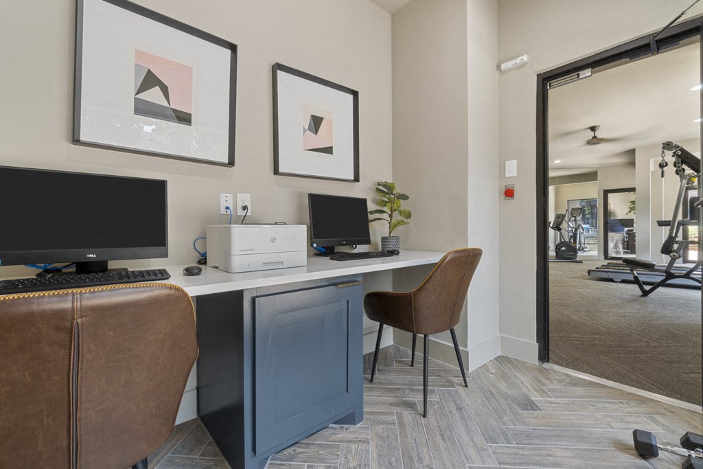 a home office with two computers and a printer on a desk