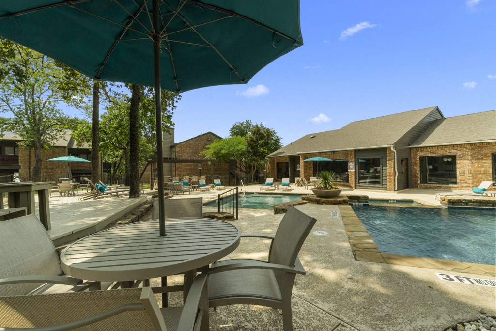 a patio with a table and chairs next to a swimming pool