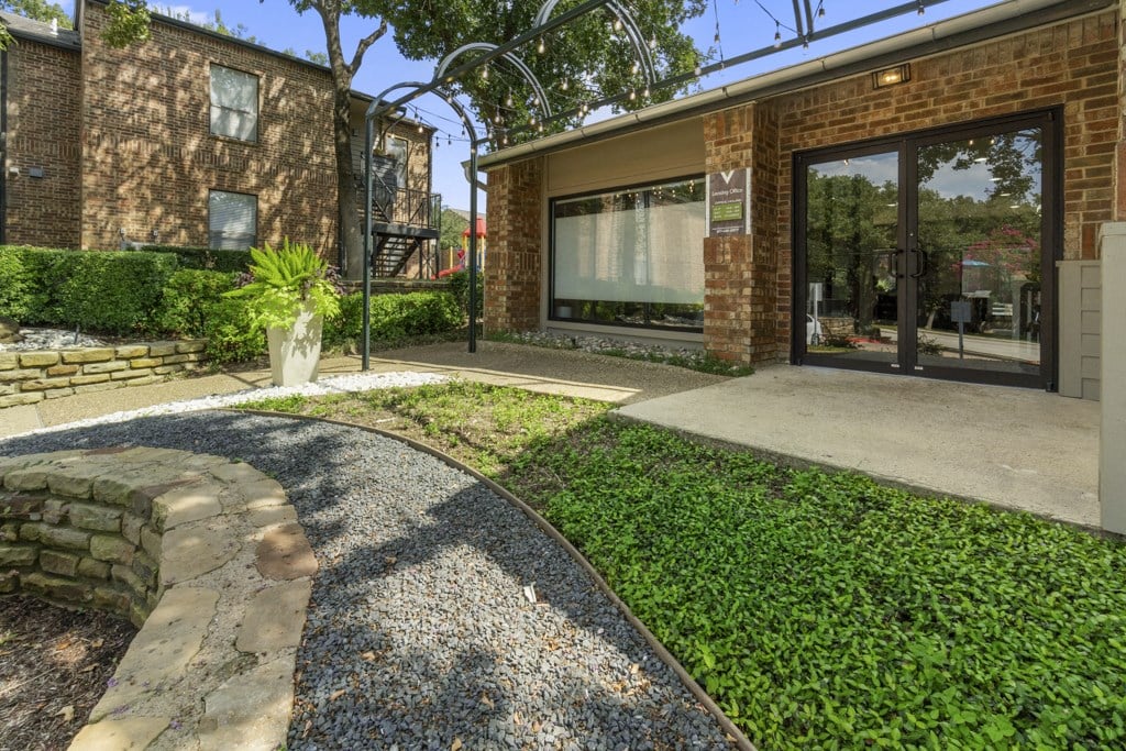 the front yard of a brick house with a sidewalk and glass doors