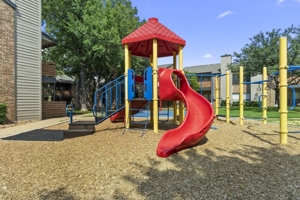 a playground with a red slide and a yellow swing set