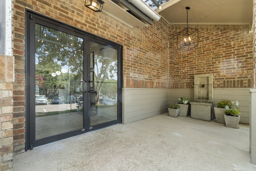 the front porch of a brick building with glass doors