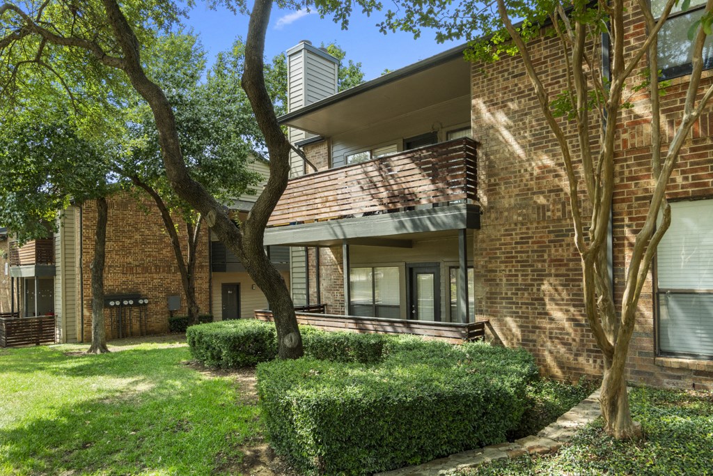 exterior view of a brick apartment building with trees and grass