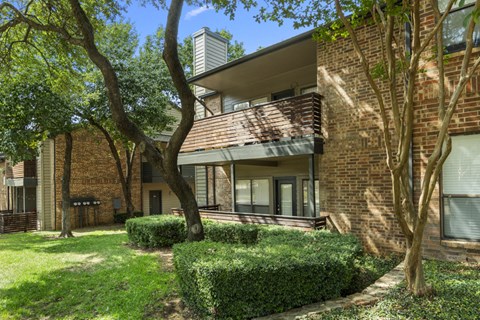 exterior view of a brick apartment building with trees and grass
