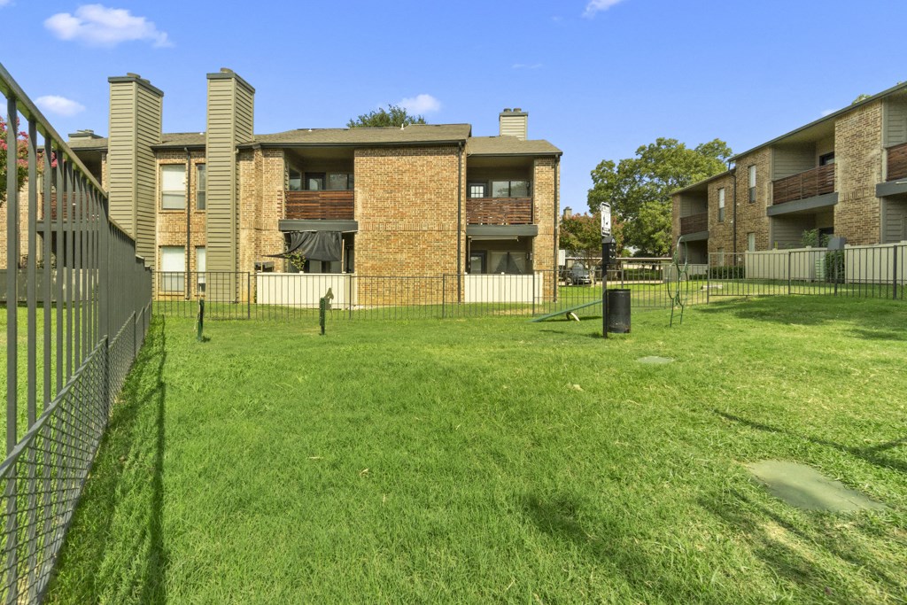 an apartment building with a grass yard and a fence