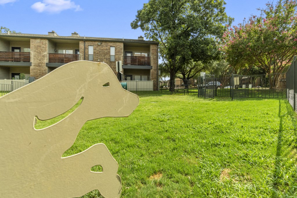 a concrete rocking horse in the grass in front of an apartment building