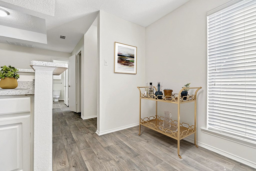 the living room and dining room of a home with white walls and wood floors