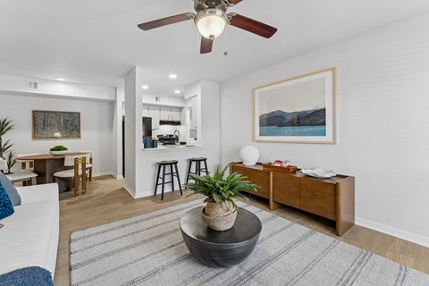 A living room with a ceiling fan, a rug, and a painting on the wall.