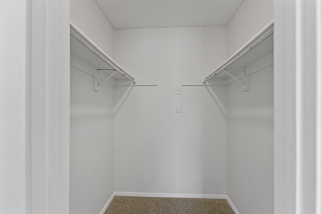 a walk in closet in a bedroom with white walls at The Hudson, North Richland Hills, TX