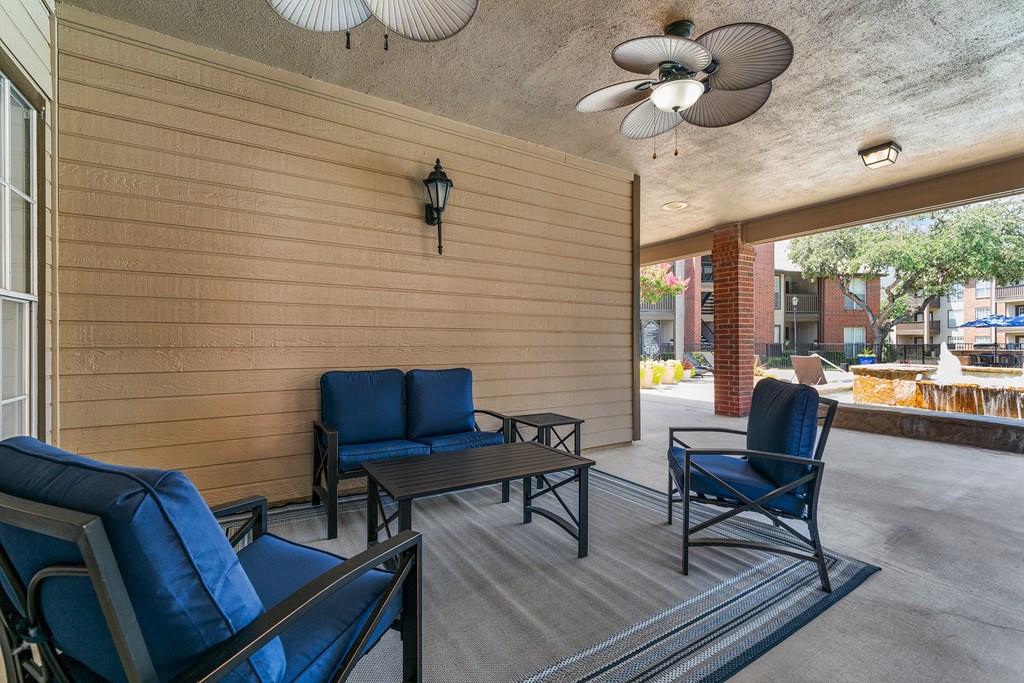 a patio with blue chairs and a ceiling fan