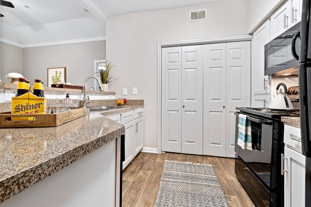 a renovated kitchen with faux granite counter tops and black appliances at Fountains of Denton in Denton, TX