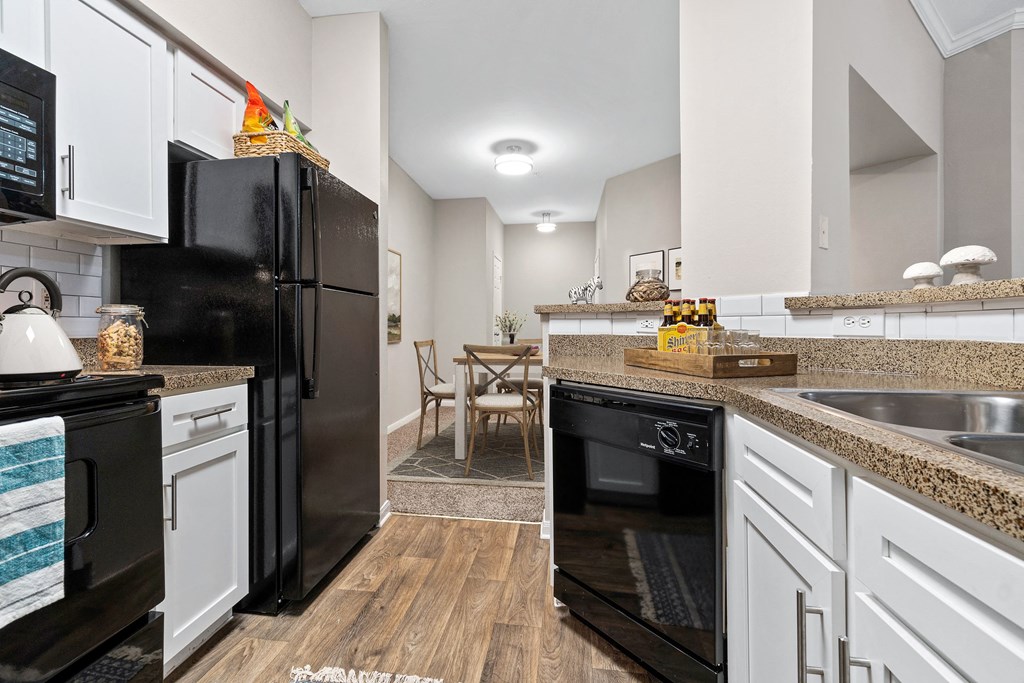 a renovated kitchen with black appliances and white cabinets at Fountains of Denton in Denton Texas