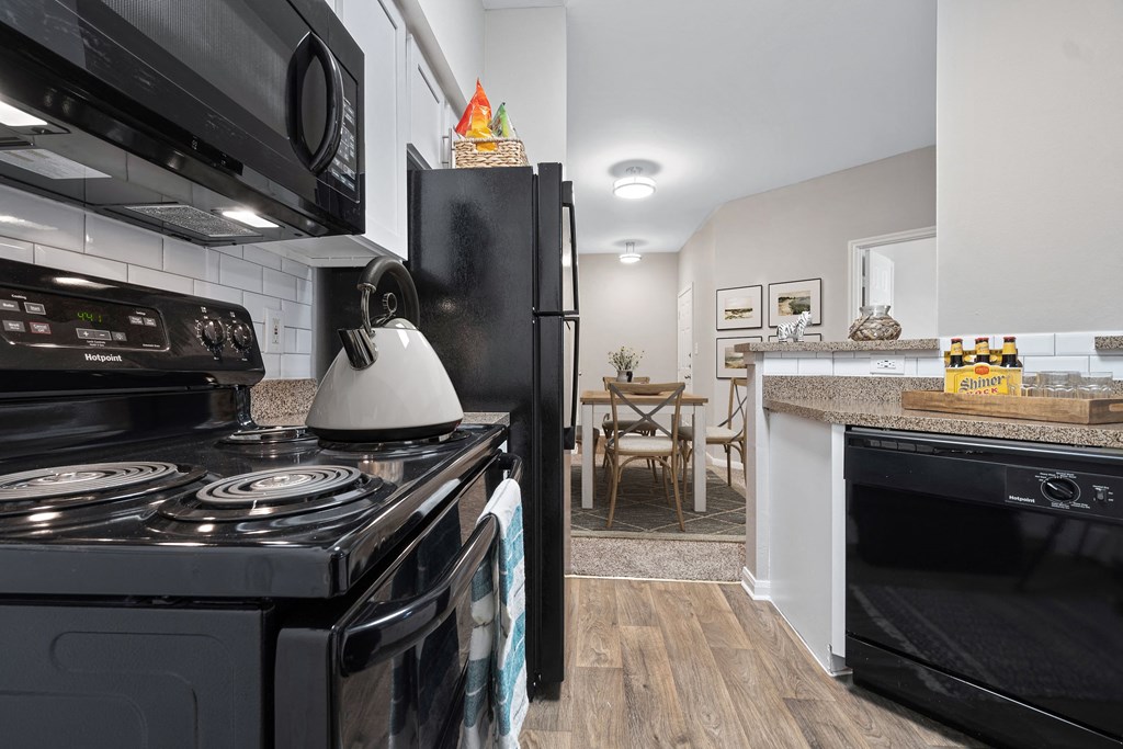 a kitchen with black appliances and a stove and a refrigerator at Fountains of Denton in Denton, TX