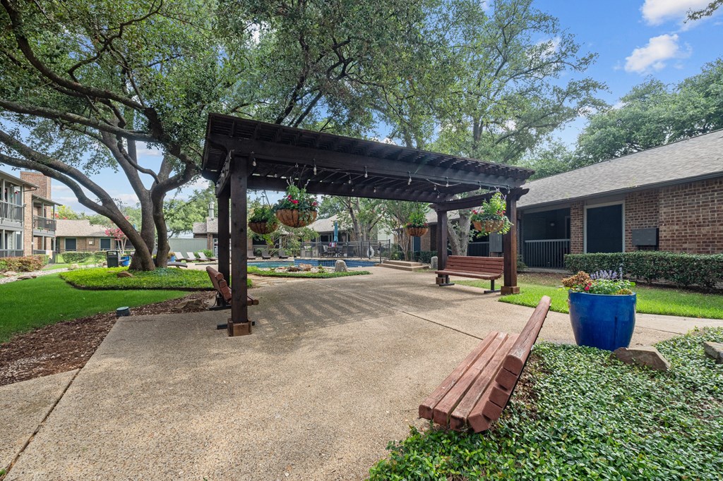 a park with a wooden bench and a pergola