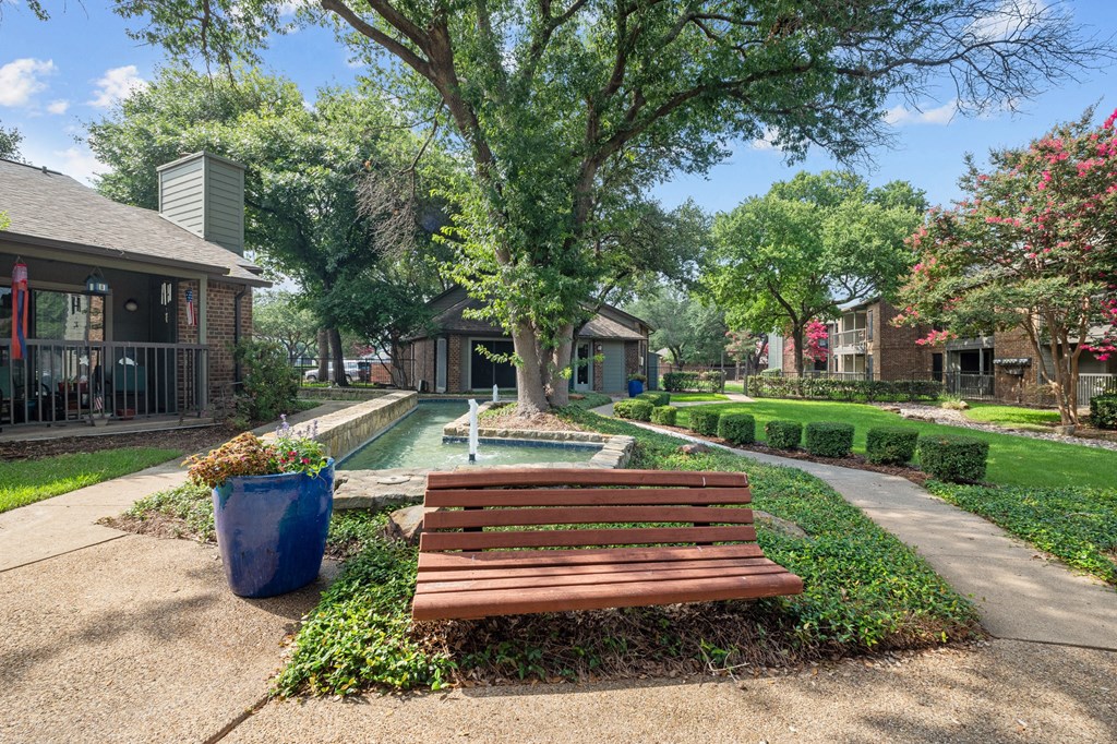 a park with a bench and a pool in the background