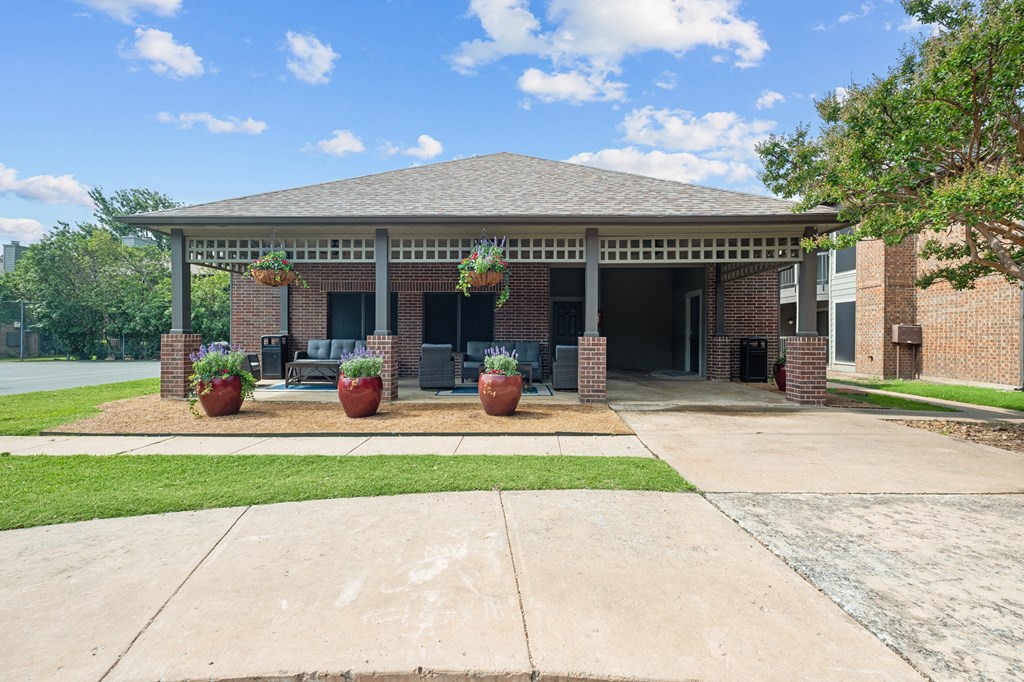 a covered patio with potted plants in front of a brick building