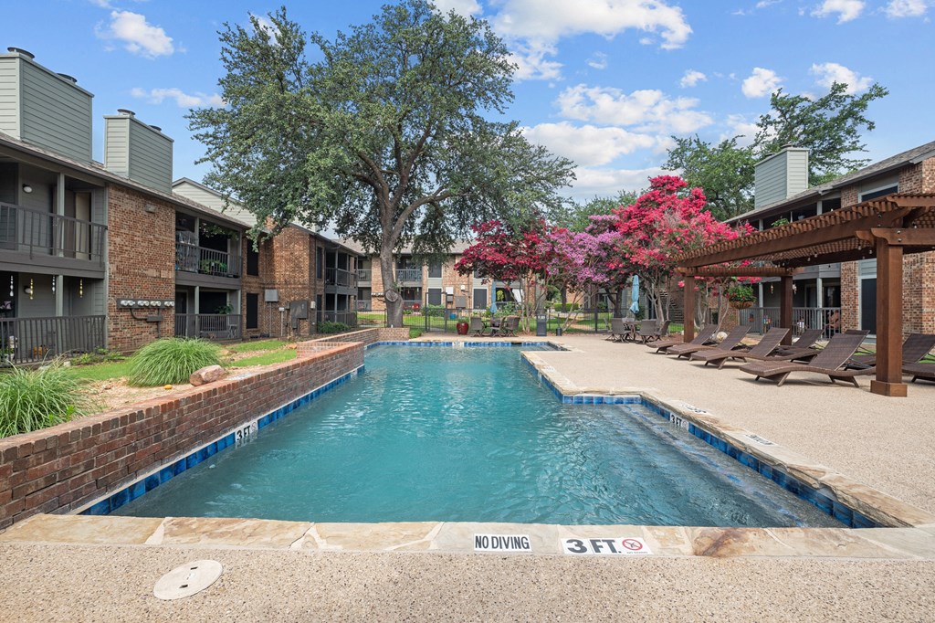 a swimming pool with lounge chairs and trees in the background