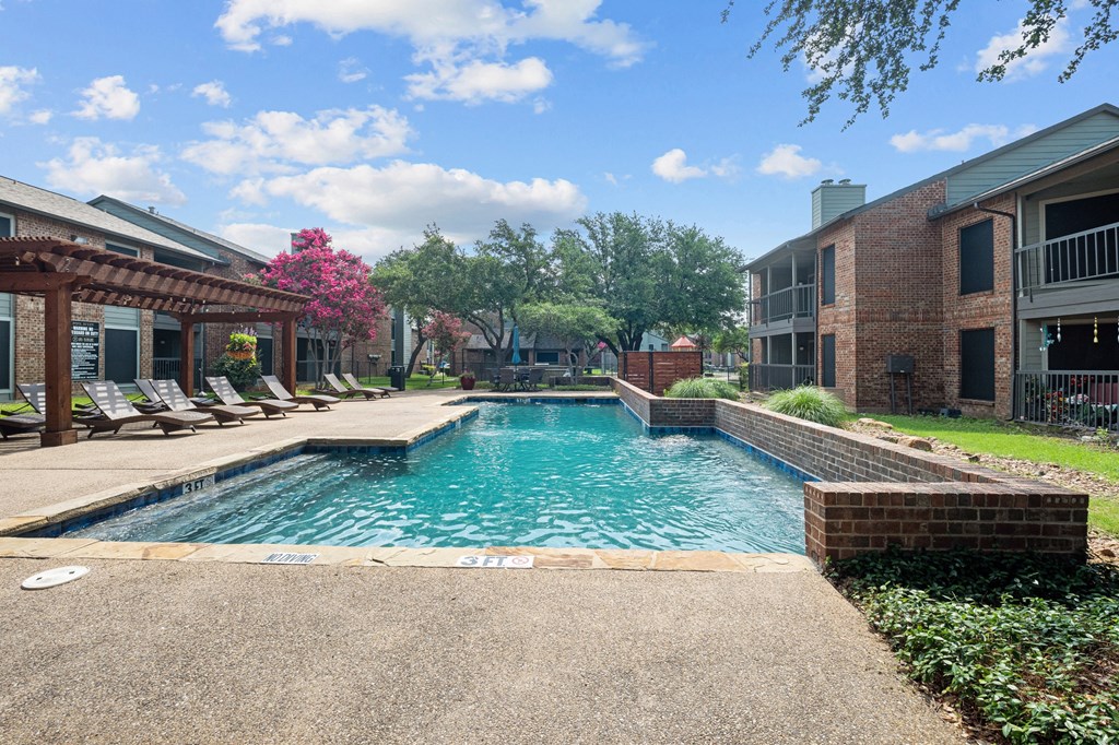 a swimming pool with lounge chairs and trees in the background
