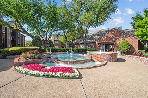 A pool surrounded by a brick wall and a flower bed.