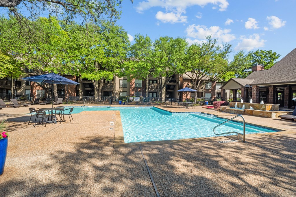 A swimming pool surrounded by trees and chairs. at Preston Bend, Dallas