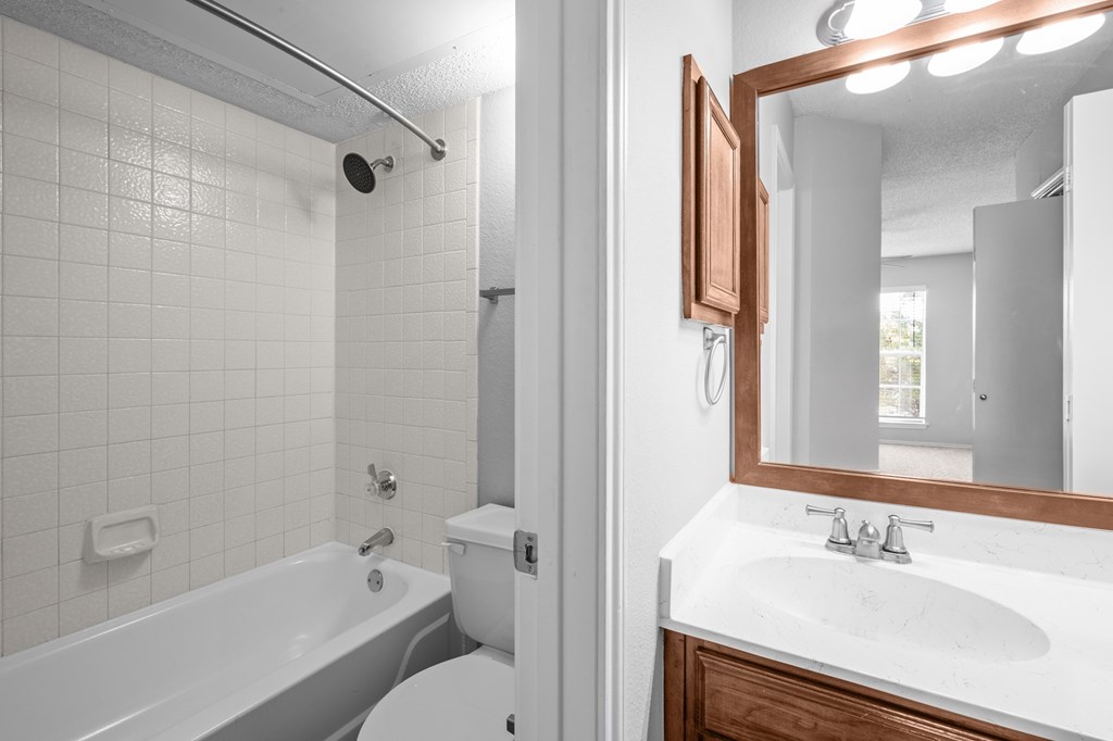 A white bathroom with a white toilet, white sink, and a white bathtub. at Preston Bend, Dallas