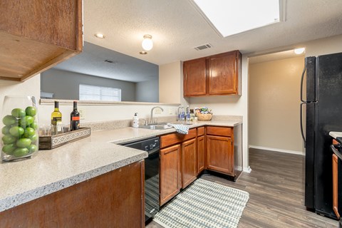 a kitchen with wooden cabinets and a counter top and a black refrigerator