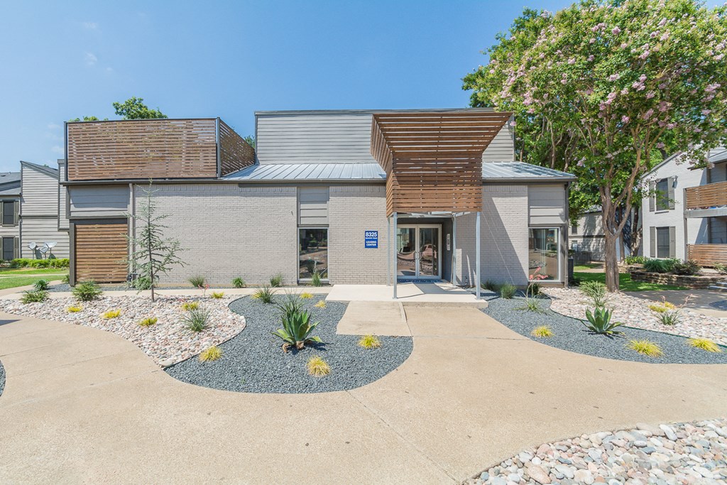the front of a house with a driveway and a tree