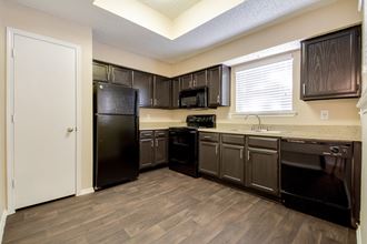 an empty kitchen with black appliances and dark cabinets