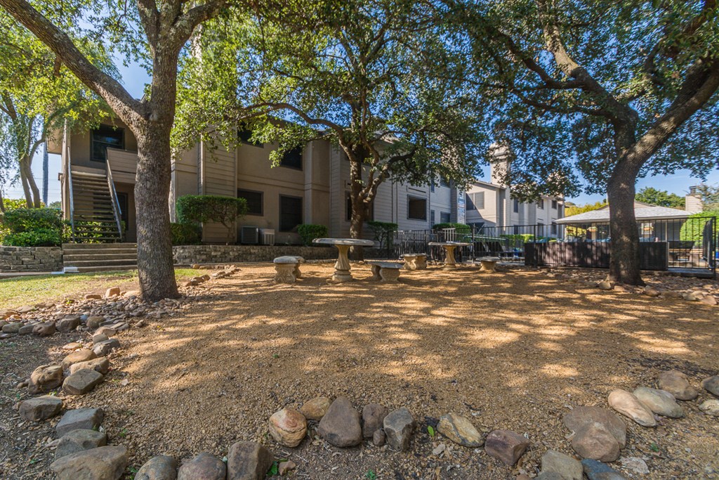 a picnic area with trees and rocks in front of a building