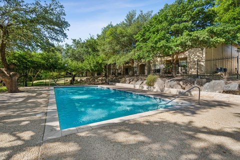 A swimming pool surrounded by trees and a house.