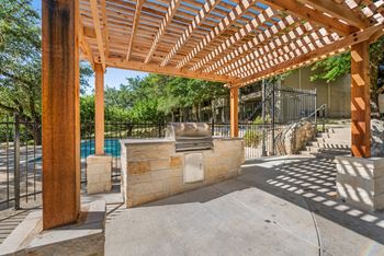 A wooden pergola with a pool in the background.