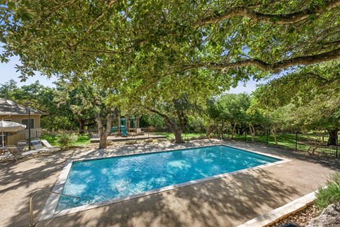 A swimming pool surrounded by trees and a fence.
