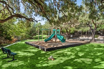 A playground with a green slide and a wooden platform.