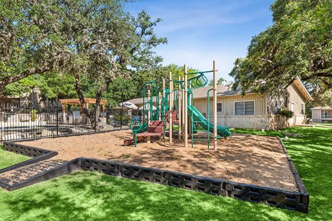 A playground with a green slide and a red and green swing set.