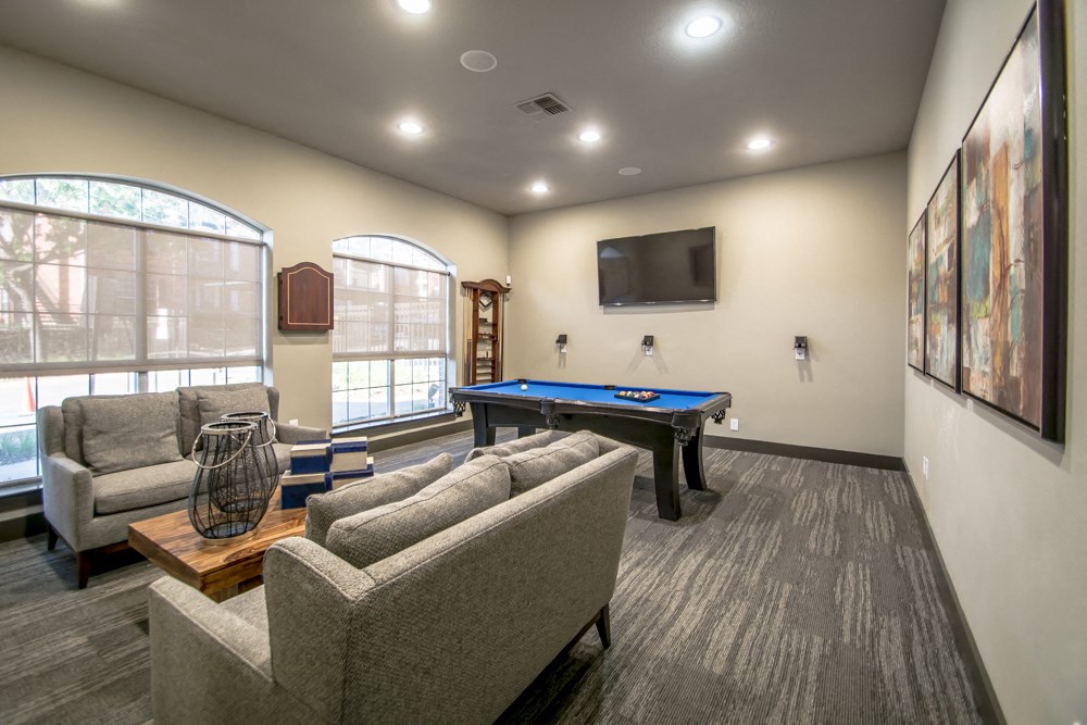 a community room with a pool table and couches