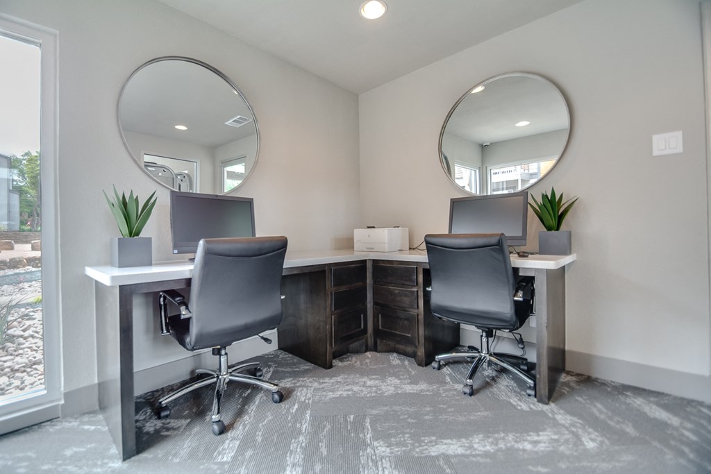 two desks with chairs in an office with two mirrors