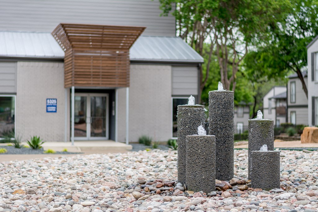a group of concrete posts in the gravel in front of a building
