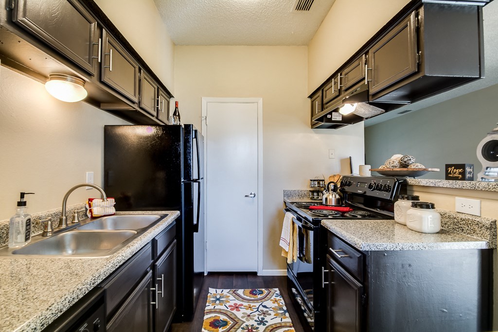 an updated kitchen with granite counter tops and black appliances