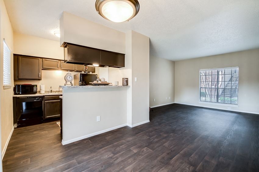 an empty living room with a kitchen and a large window