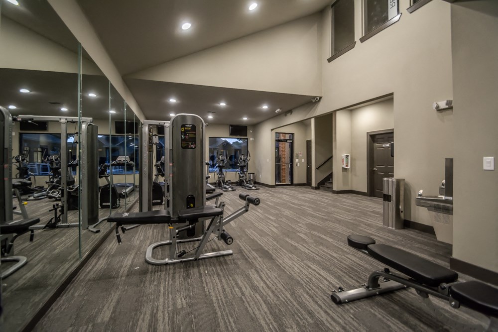 a gym with exercise equipment and mirrors in a building