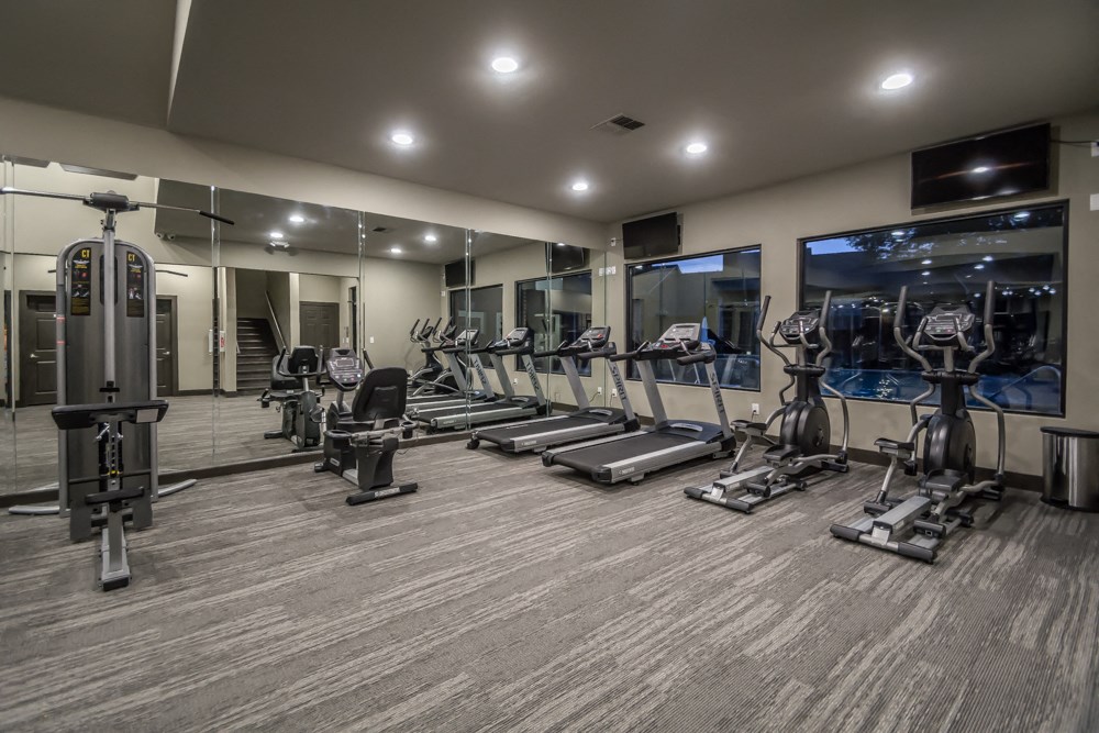 a gym with cardio equipment and mirrors in a building