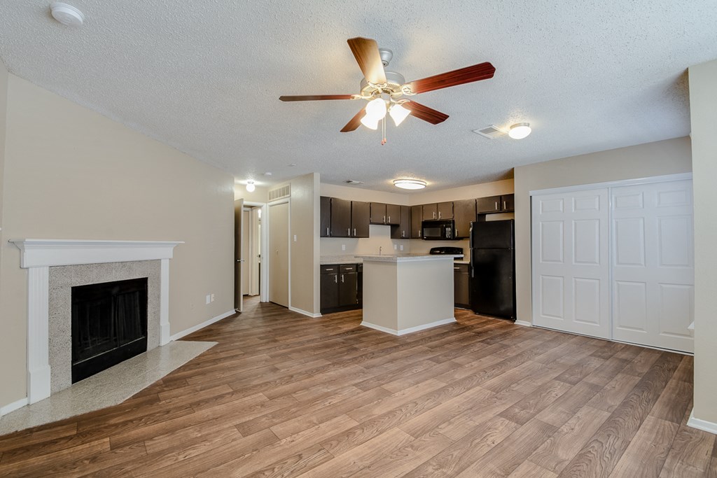 an empty living room with a fireplace and a kitchen