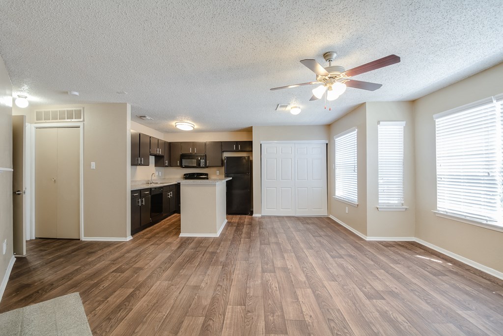 an empty living room and kitchen with a ceiling fan