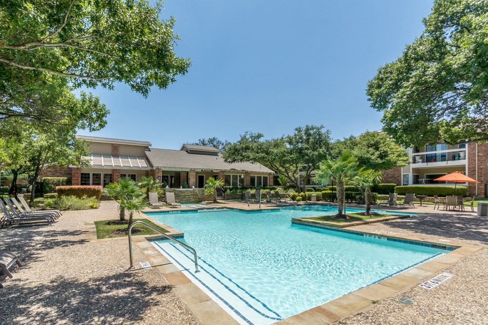 a swimming pool with trees and a building in the background