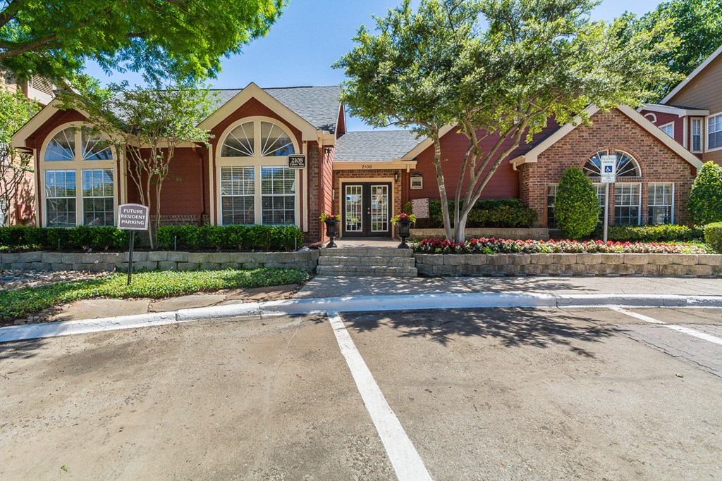 a large brick house with a driveway and trees in front of it
