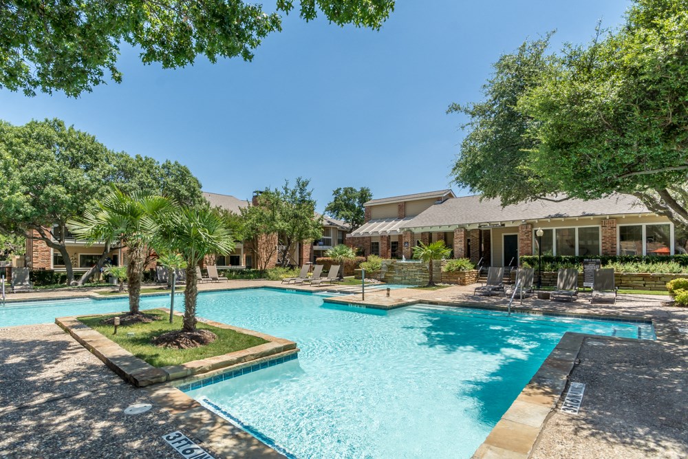a swimming pool with trees and a house in the background