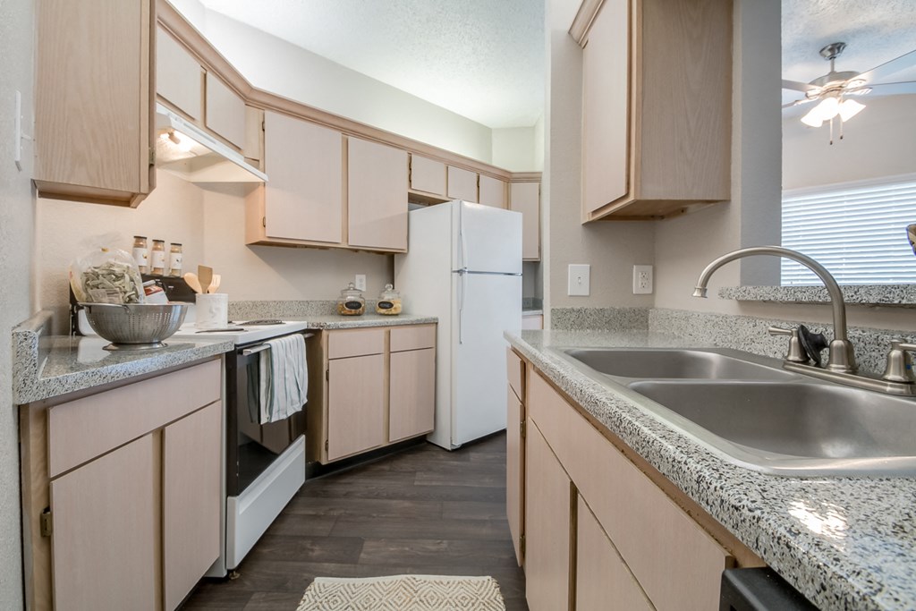a kitchen with granite counter tops and wooden cabinets and a sink