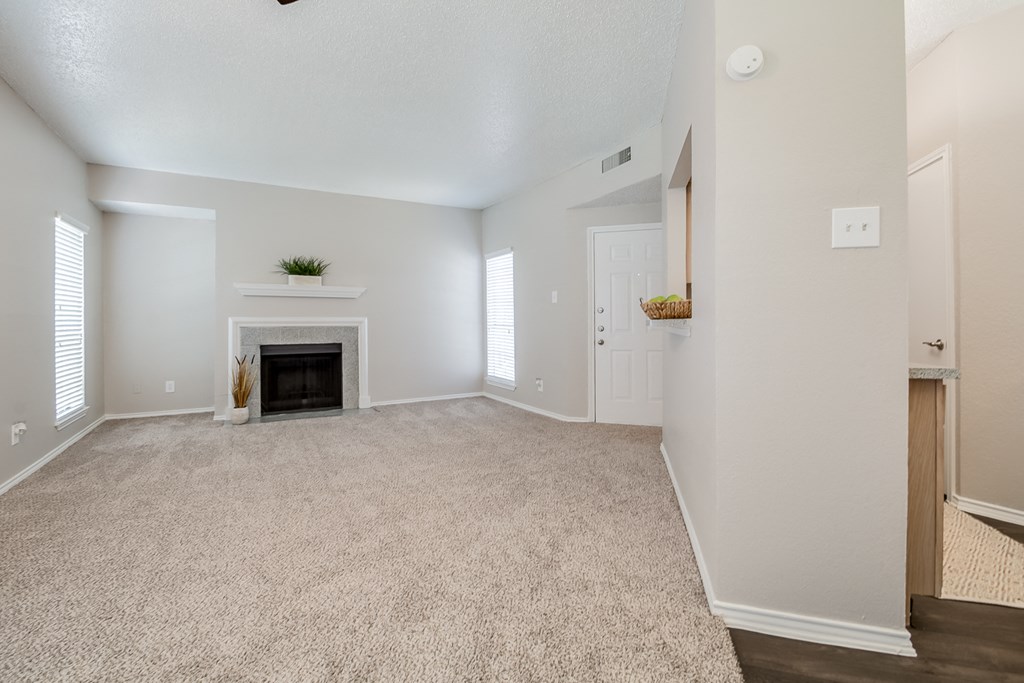 an empty living room with a fireplace and white walls