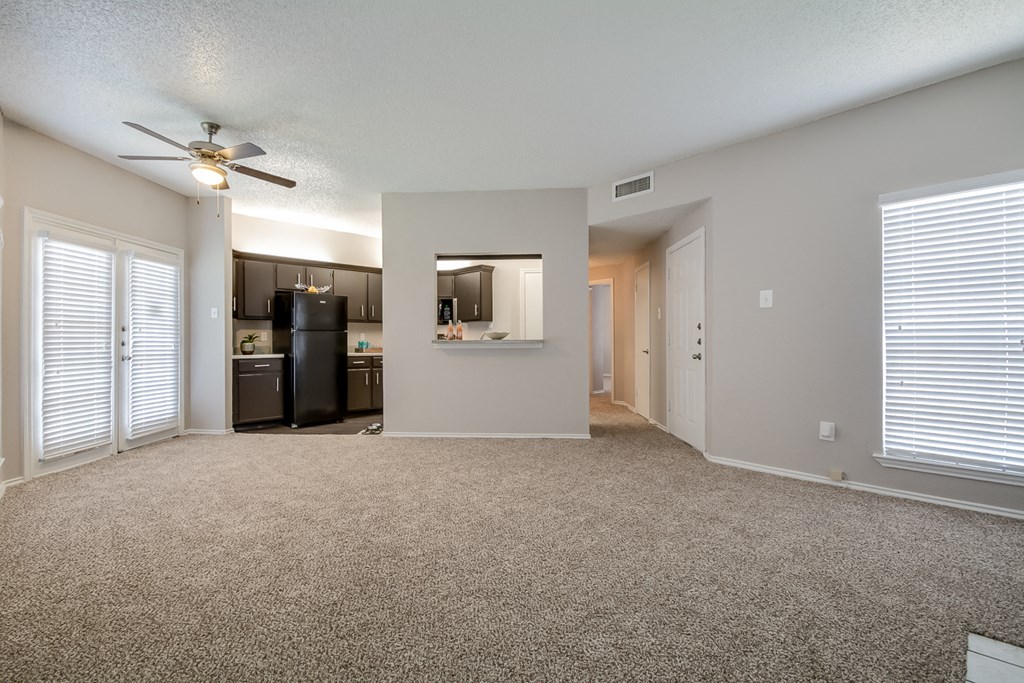 A spacious room with a ceiling fan and a carpeted floor.
