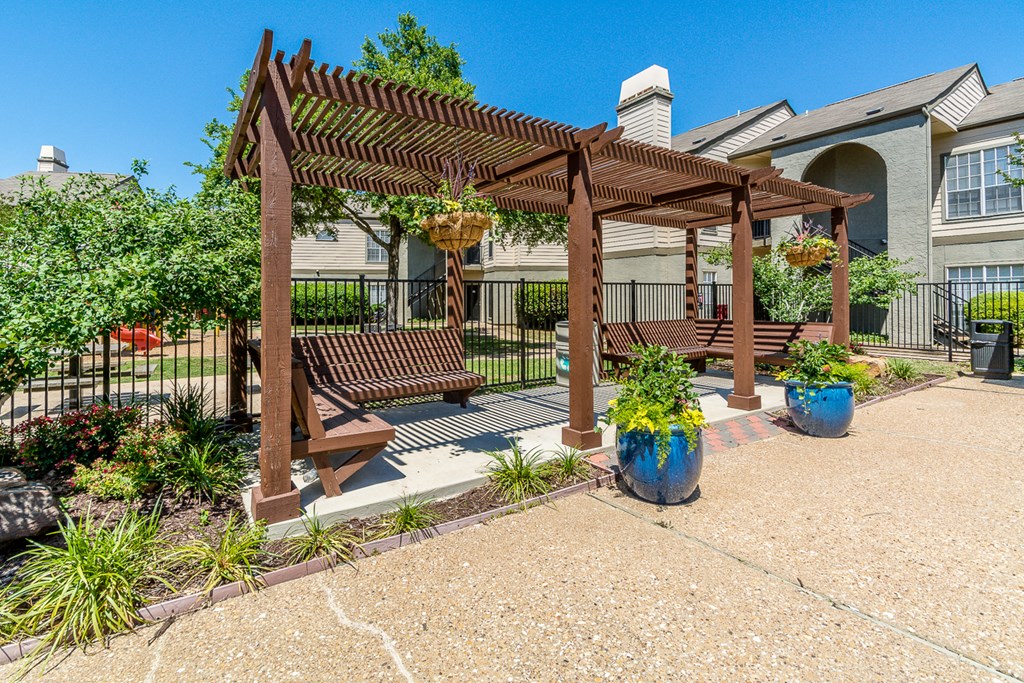 A wooden pergola with a bench and potted plants.